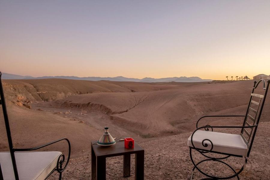 Private desert camp terrace with Moroccan tagine pot and Atlas Mountains panorama at sunset — Agafay
