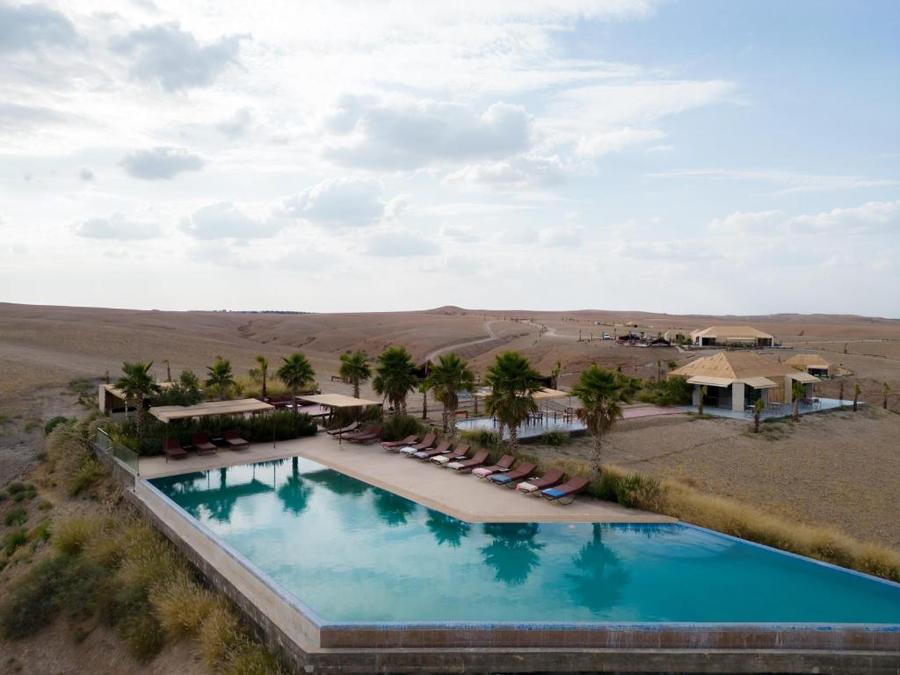 Aerial view of large luxury infinity pool with sun loungers and desert landscape — Agafay camp Marrakech