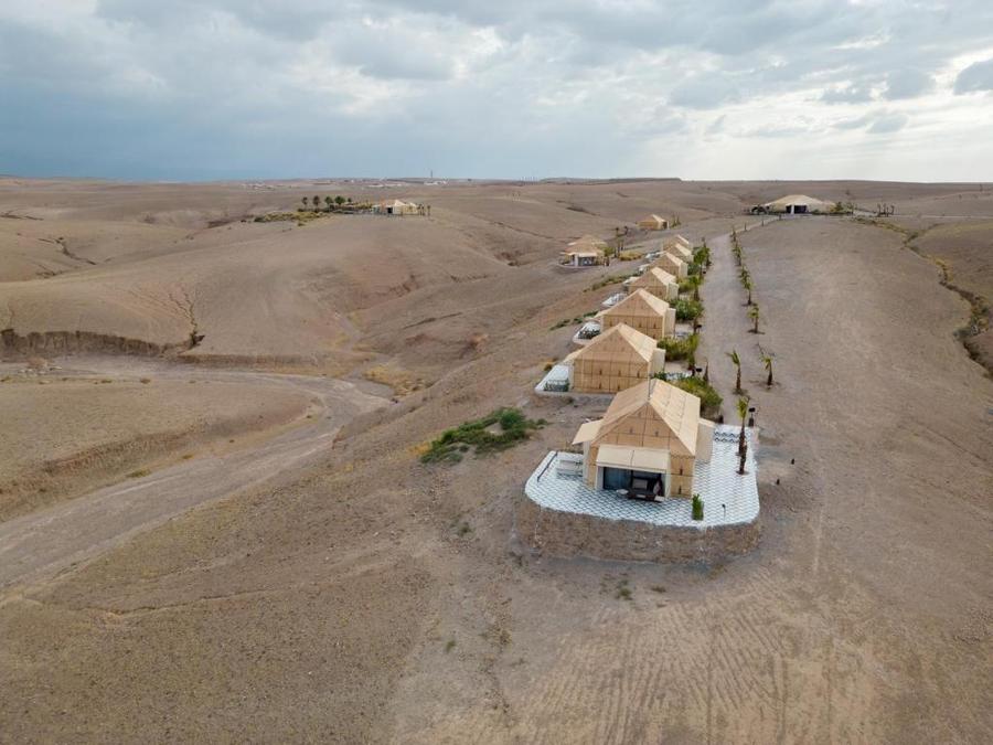 Aerial drone view of luxury tent camp stretching through Agafay Desert landscape near Marrakech