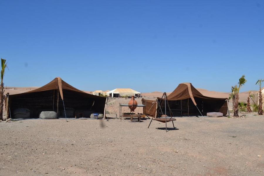 Traditional brown Berber nomad tents in open Agafay Desert under clear blue sky — authentic camp