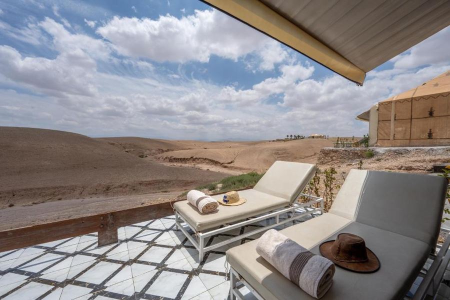Private terrace with two white sun loungers facing Agafay Desert panorama — luxury tent camp Marrakech