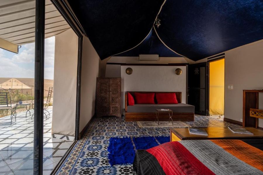Luxury tent interior with deep blue ceiling, zellige tile floor and desert terrace view — Agafay camp