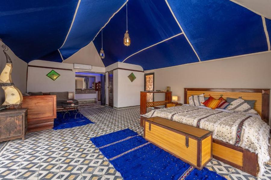 King bedroom in luxury desert camp with blue ceiling and traditional Moroccan furnishings — Agafay