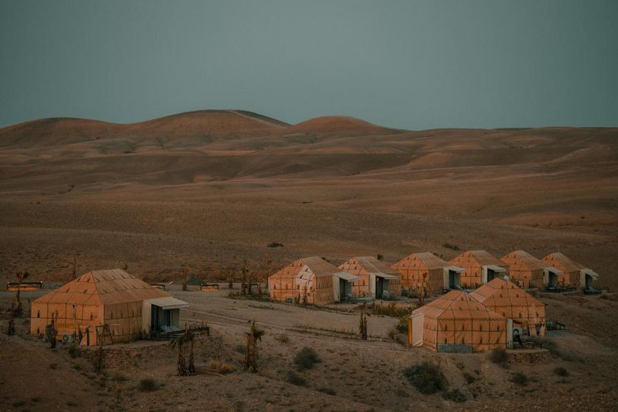Luxury desert camp tents illuminated in golden hour sunset light — Agafay Desert near Marrakech