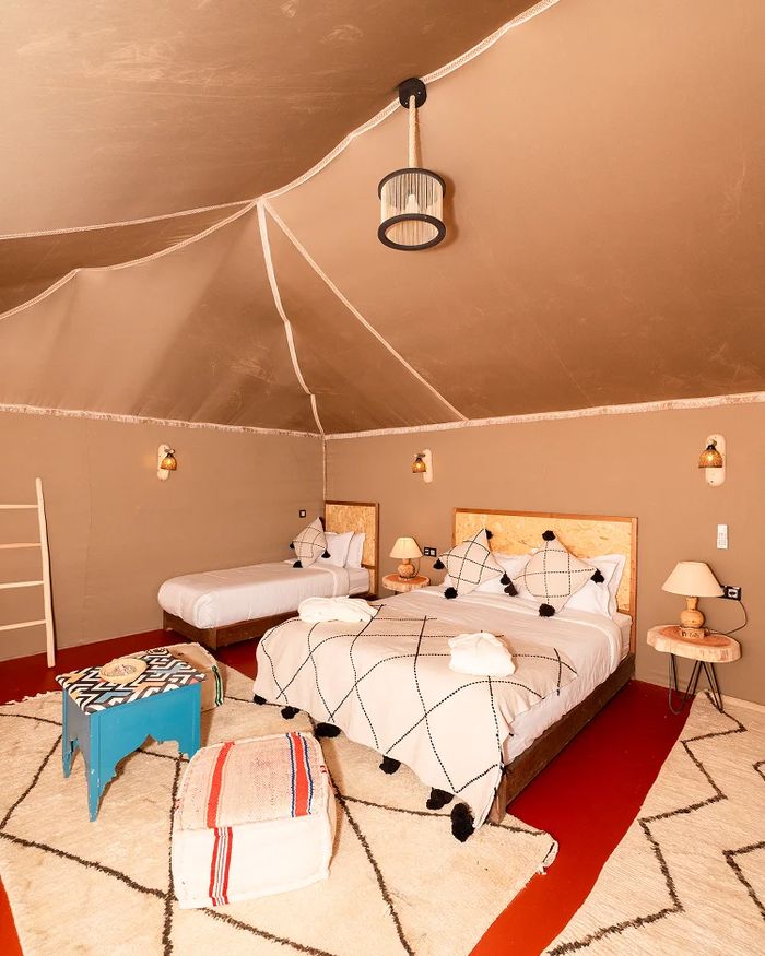 Family desert camp tent with two beds, white Beni Ourain carpet and warm Moroccan decor — Agafay