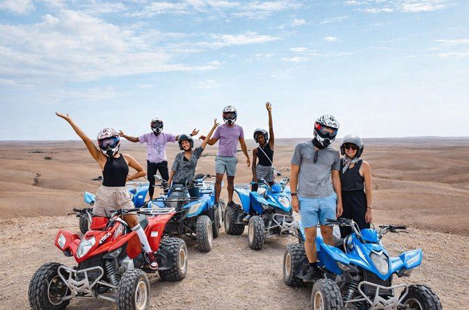 Grupo de mujeres en quad en el desierto de Agafay, brazos en alto