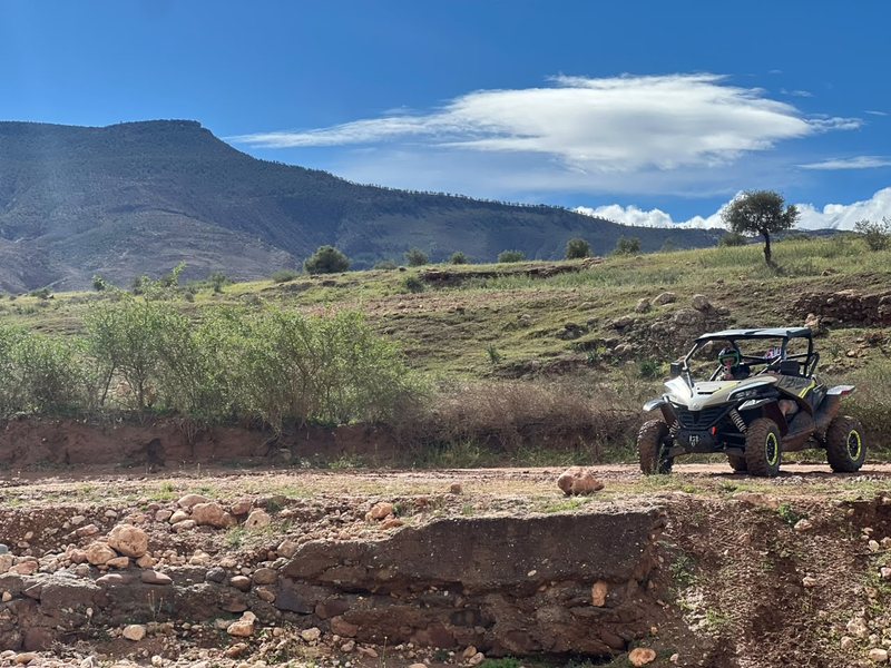 Buggy en una pista de tierra con colinas verdes y una montaña al fondo
